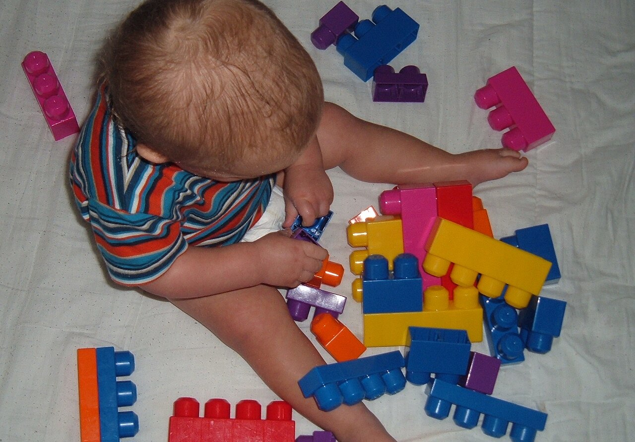 Child playing with large building blocks on the floor