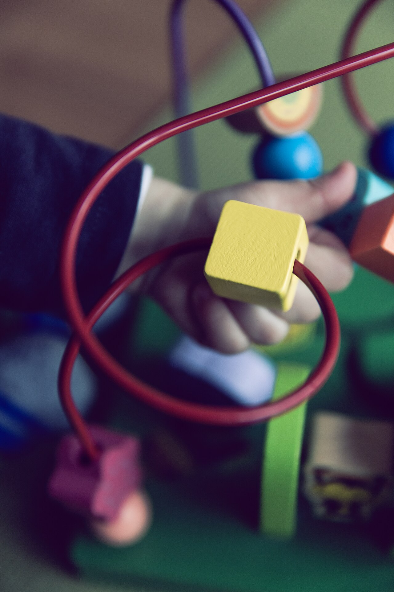 Toddler's hand moving beads on a wire maze toy